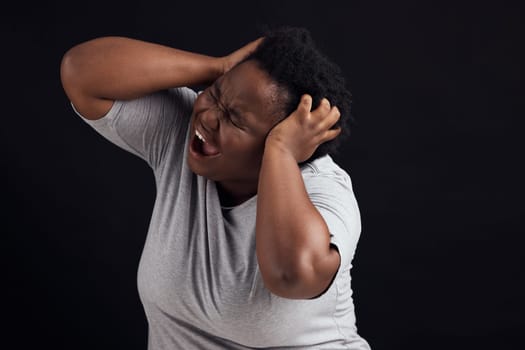 Frustrated, scream and black woman with anxiety, mental health and lose control on a dark studio background. Emotion, screaming or model with depression, shouting and pain with burnout or expression