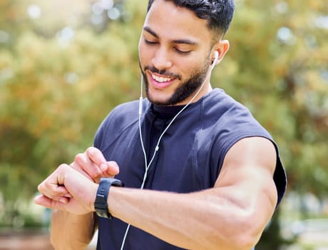 Set the clock and just go for your goals. a sporty young man listening to music and checking his watch while exercising outdoors.