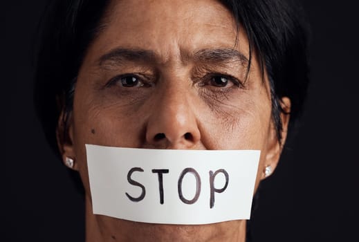 Portrait, stop and silence with a woman in studio on a black background for gender equality or domestic violence. Face, censorship or abuse and a scared female victim with her mouth covered closeup