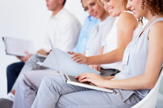 Waiting room, laptop and business people for recruitment information, job search or human resources opportunity. Professional woman in chair typing on computer, resume update or CV for online hiring