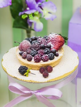 Fresh berry tarts filled with custard, raspberry, blueberry, powdered sugar and blackberry delicious dessert.
