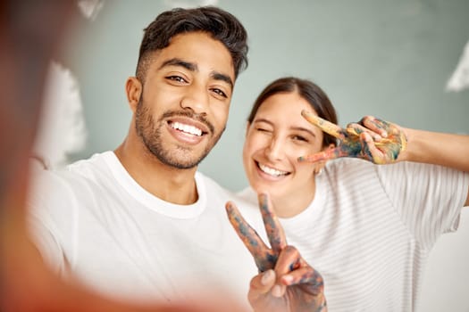 Cheers to the DIY challenge. a young couple taking a selfie while painting together at home.