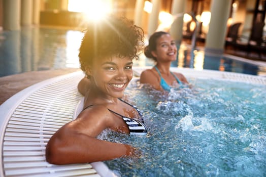 Happiness is a well-deserved vacation. Portrait of a woman relaxing in a jacuzzi with her friend blurred in the background.