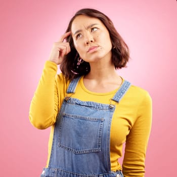 Confused woman, thinking and scratch for ideas in studio, pink background and emoji for doubt, why and problem solving. Asian model daydream of decision, remember memory and brainstorming questions