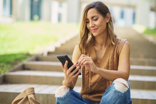 Middle aged woman using her smartphone with a pen or stylus, outdoor. Caucasian female wearing casual clothes.