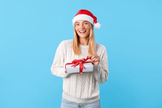 Smiling woman with gift in Santa ha
