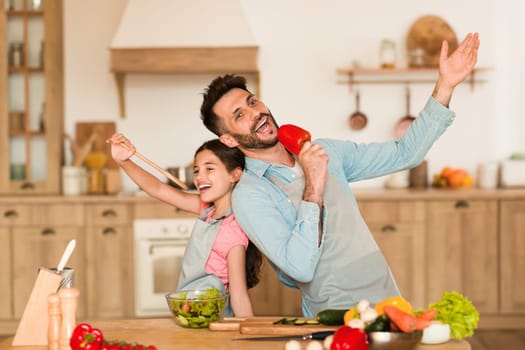 Father and child singing with kitchen props