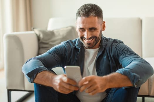 Middle aged man lounging with his smartphone sitting at home