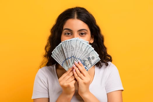 Happy satisfied indian woman holding bunch of money banknotes