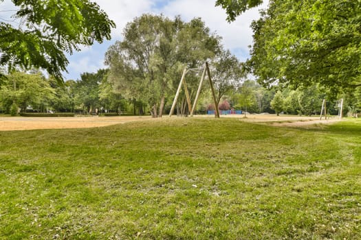 a swing set in a park with grass and trees