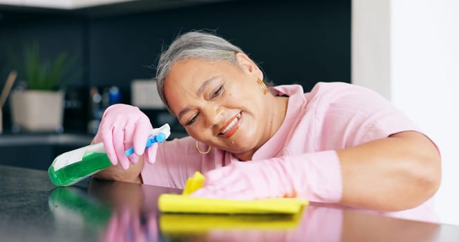 Cleaning, mature or woman by detergent on kitchen counter, housekeeper pride or smile for home hygiene. Happy, person and hand for housekeeping to shine, sanitizer and disinfectant surface in house