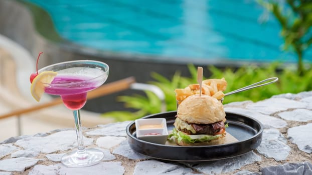 Hamburger and a cocktail at lunch at a restaurant looking out over the swimming pool