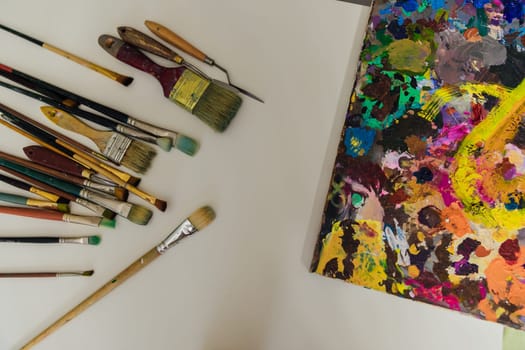 paint brushes lie next to the artist's paint palette