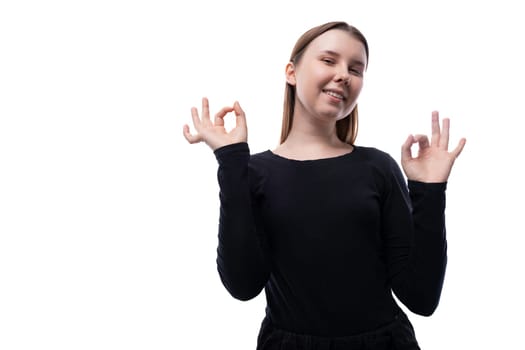 Portrait of a smiling happy Caucasian pre-teen girl wearing a black turtleneck on a white background