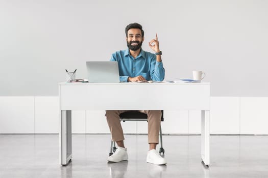 Indian businessman having idea, sitting at desk