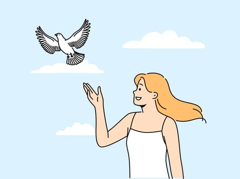 Woman releases dove standing under summer blue sky and watching bird symbolize hope and peace