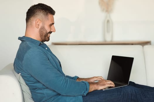 middle aged man smiles while working remotely on laptop indoors