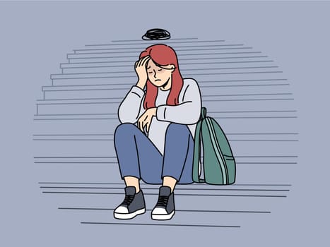 Teenage woman cries because bullying or harassment and sits on steps suffering from social problems