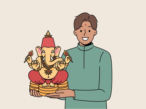 Indian man holds figurine Lord ganesha and smiles demonstrating amulet that brings good luck
