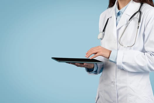 Close-up of female doctor with tablet over blue background