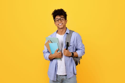 Happy black student guy with books and backpack