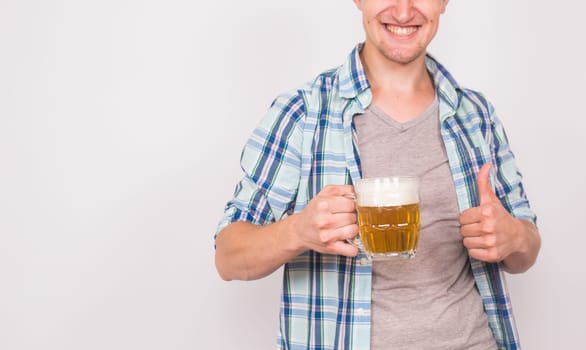 Close up of young man holding beer mug and showing thumbs up