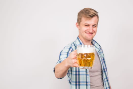 Young handsome man holding a mug of beer. Background with copy space.