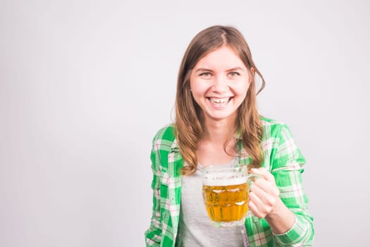 Cheerful young woman holding a beer mug full of beer and smiling on white background