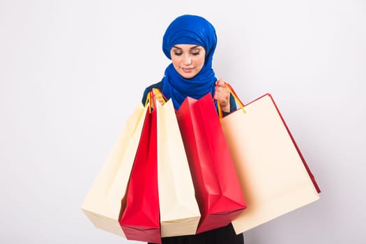 Happy young muslim woman with shopping bag on white background