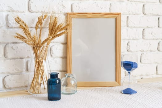 Vase with ears of wheat and photo frames against brick wall