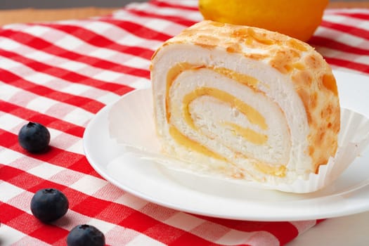 Meringue roll cake with cream on wooden table