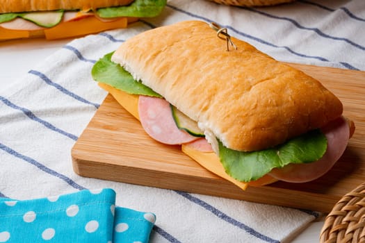 Fresh sandwich with sausage and lettuce on table
