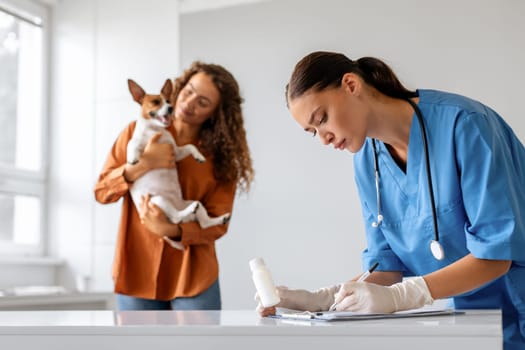 Veterinarian writing prescription, owner with dog