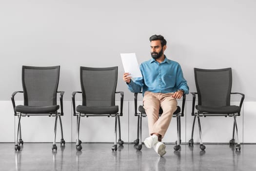 Indian man analyzing document in job interview waiting room