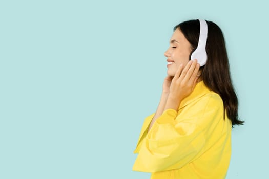 Adorable joyful young woman in yellow shirt listening to music