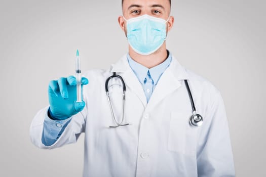 Male doctor in mask holding a syringe