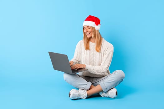 Focused woman with laptop wearing Santa hat
