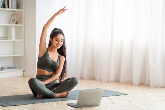 Fitness at home: Woman stretches with laptop