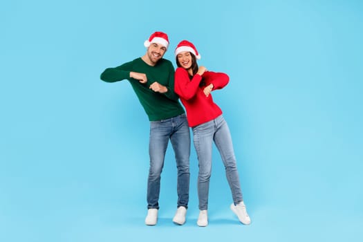 couple in Santa hats dancing on Christmas party, blue background