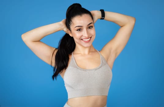 Happy sporty attractive young woman in sportswear on blue