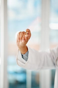 Hand holding medicine, tablet and healthcare doctor holding a pill for remedy, cure for sickness and medication for good health. Closeup of a medical professional showing a vitamin or supplement