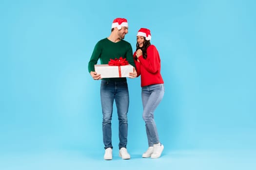 Man giving Xmas gift box to woman over blue background