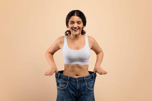 Weight Loss Result. Happy Young Indian Woman Posing In Oversized Jeans