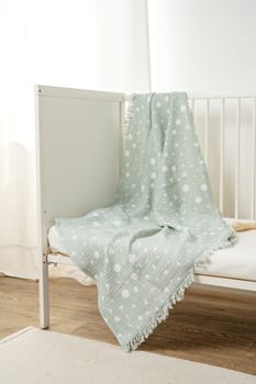 Muslin baby blanket hanging on child's bed in nursing room