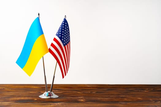 Small flags of USA and Ukraine on flagpoles close up