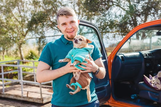 Funny portrait of a young man holding a cute chihuahua dog