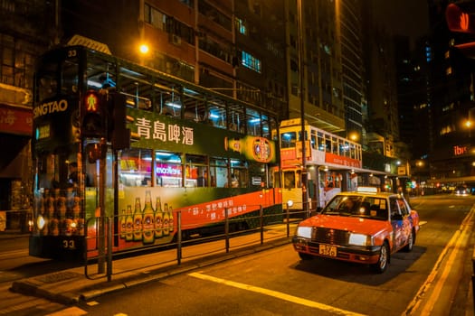 Hongkong 10 February 2017, a red taxi car with a double decker bus at night in the city of Hong Kong