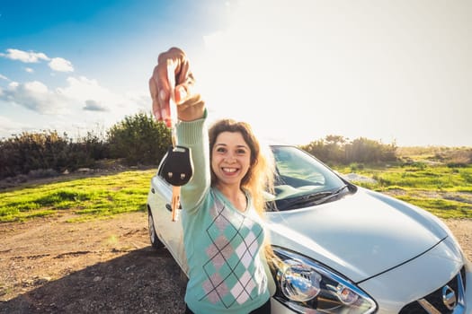 happy woman driver hold car keys near her new car