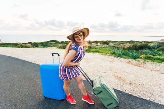 Happy traveler woman with suitcase on the road and laughs. Concept of travel, journey, trip