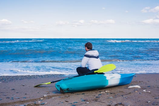 Man sitting on the beach with kayak